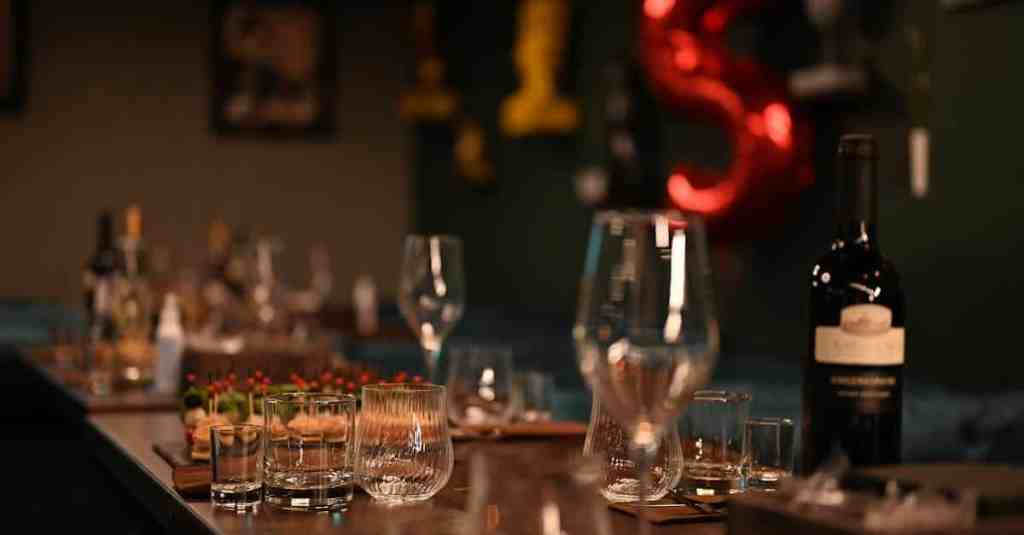 An indoor table setup featuring wine bottles and glassware, creating an elegant ambiance for a dinner event.