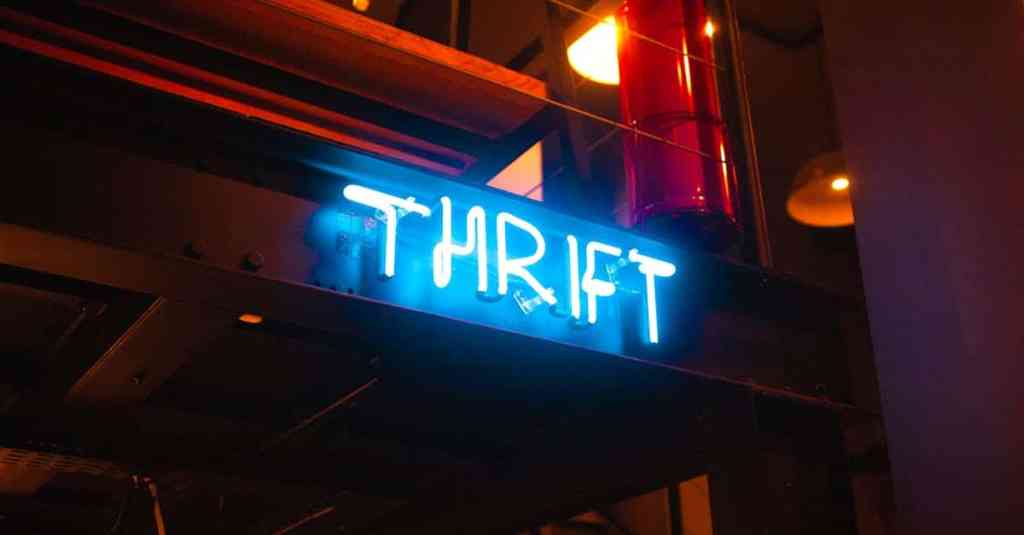 Un llamativo letrero de neón con la palabra «THRIFT» brilla en un evocador espacio interior.