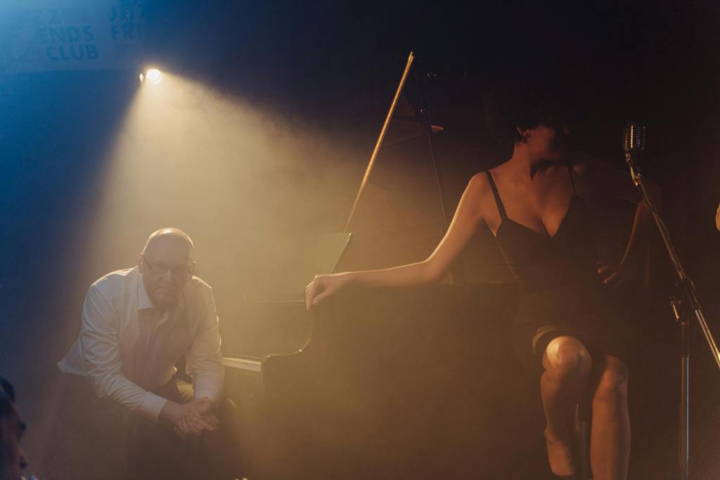 Moody jazz club performance featuring a pianist and singer on stage.