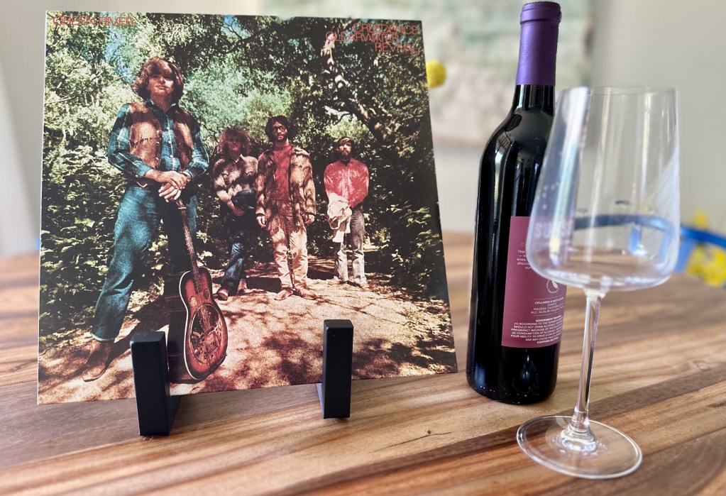 Creedence Clearwater Revival Green River vinyl album displayed with a bottle of Cline Ancient Vines Zinfandel and a wine glass for the Needle & Vine pairing.