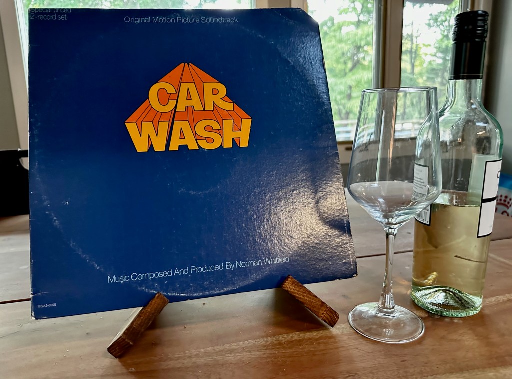 Car Wash soundtrack album displayed beside a wine glass and bottle.